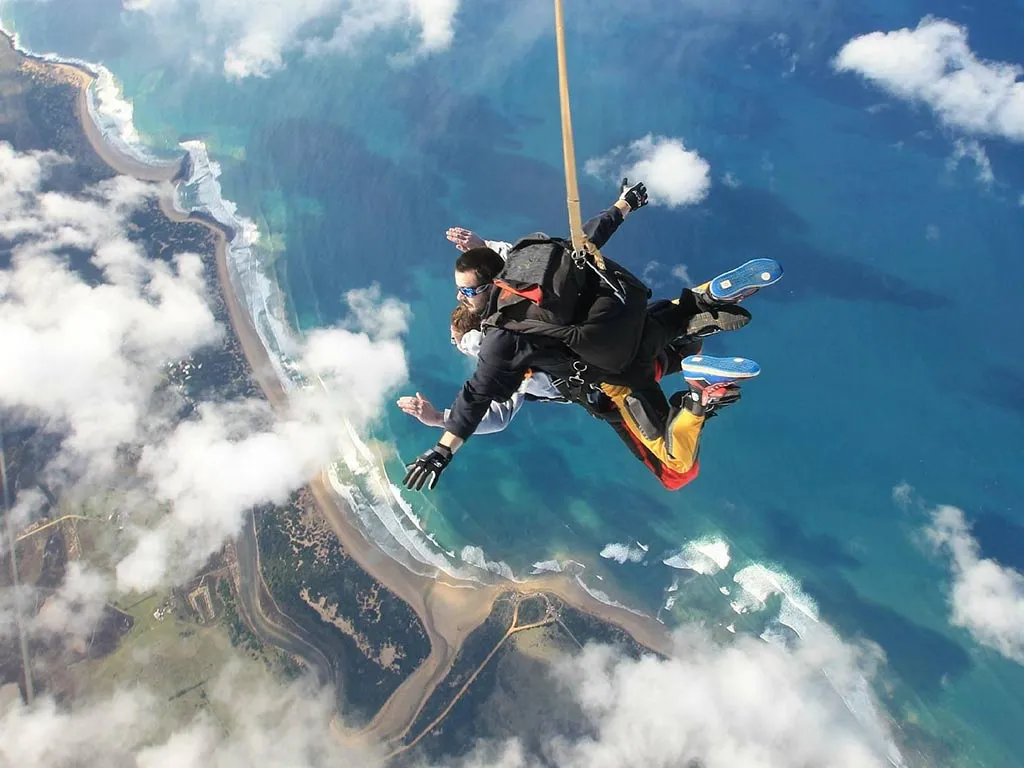 A skydiver in freefall above the rugged Great Ocean Road coastline
